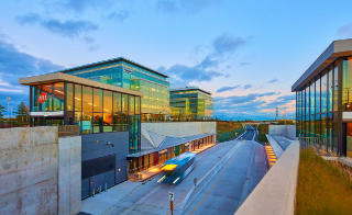 Modern transit station with glass buildings and roadway.