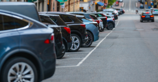 Urban street parking with a row of cars lined along a city road.