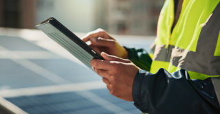 Technician using tablet to monitor solar panels on site.