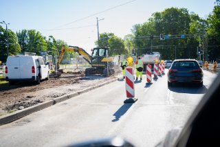 Construction workers are seen repairing a road, utilizing heavy machinery and tools to enhance the roadway