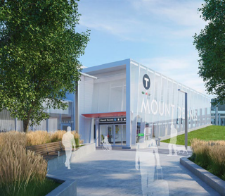 Modern transit station entrance with glass façade and landscaped walkway.