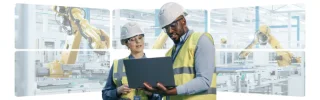Two individuals wearing hard hats and safety glasses are focused on a laptop
