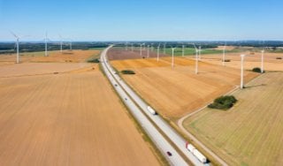 Aerial view of multiple wind turbines scattered across a landscape under a clear blue sky