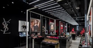 Luxury cosmetics retail store interior with YSL branding, modern lighting, and organized product displays.