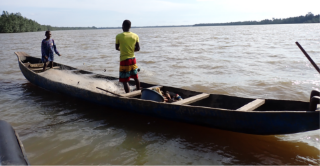Fishermen casting nets from a small wooden boat on a river.