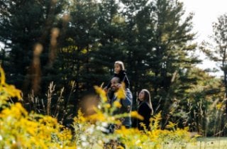 A family stands together in a vibrant field of yellow flowers