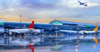 Airport terminal with parked planes and runway at dusk.